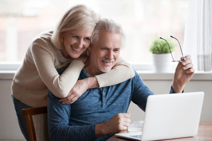 A photo of a couple at a laptop.