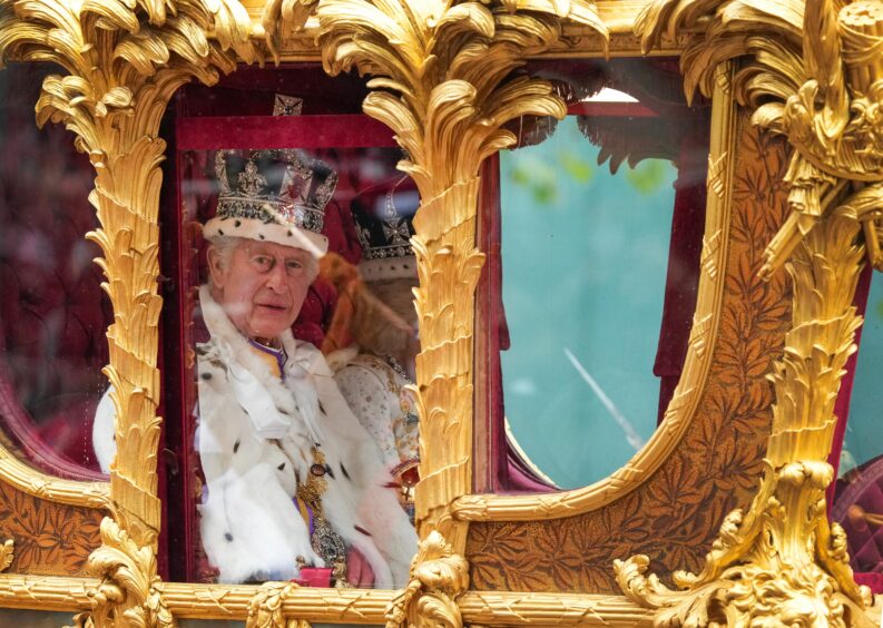 King Charles lll looks on from the carriage beside during the Royal Procession following the coronation 