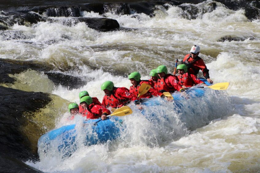 People in a kayak going over rapids.