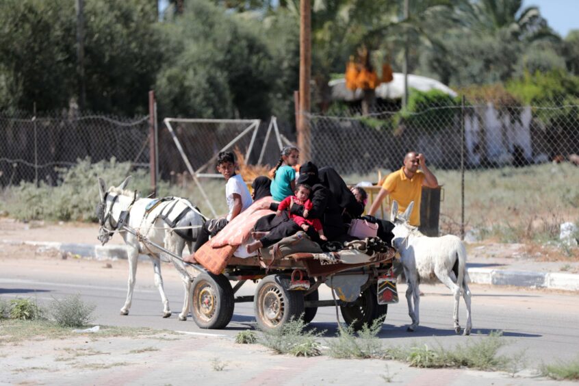 Palestinians on foot and donkey-led cart carry what they can through the rubble-strewn streets of Gaza City on Friday in search of refuge.