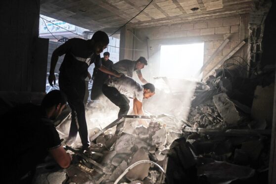 Palestinians try to rescue survivors from the rubble of a building following an Israeli strike in Khan Yunis in the southern Gaza Strip.