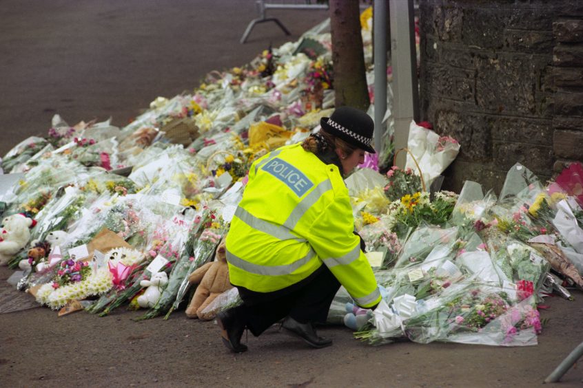 A police woman lays flowers at the gates of Dunblane Primary School after a vigil.