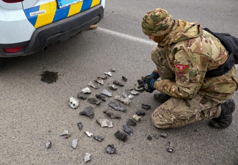 Evidence is collected by a military expert at the scene of a shelling attack.