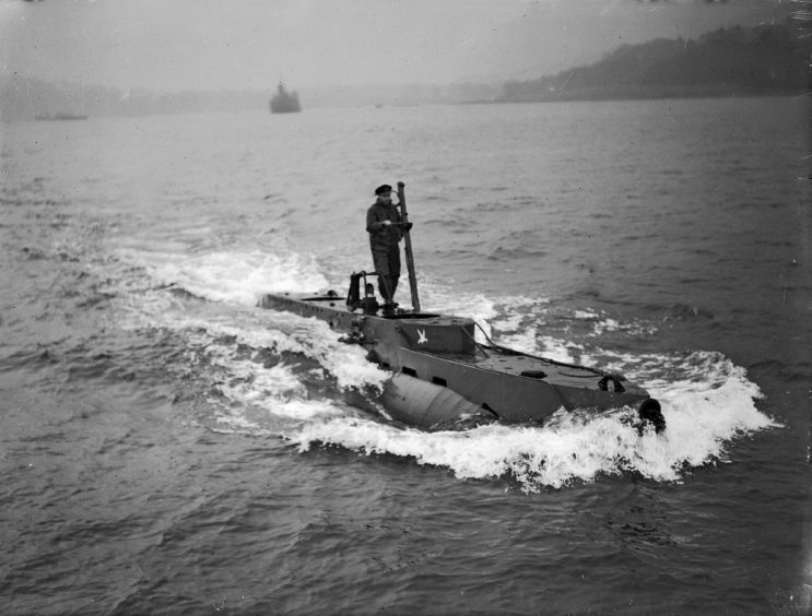 Lieutenant J. E. Smart rides on top of an X craft in the waters of Scotland. It was built using scientific information from Haldane’s experiments – was used to guide troops into the beaches.