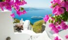 A cruise ship sails by the Greek island of Santorini, a popular honeymoon destination.