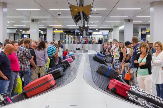 Passengers collect their bags at the carousel.