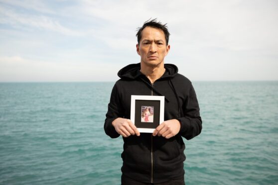 Barton Williams, who was evacuated from Vietnam as a child, holds a picture of himself back in his homeland.