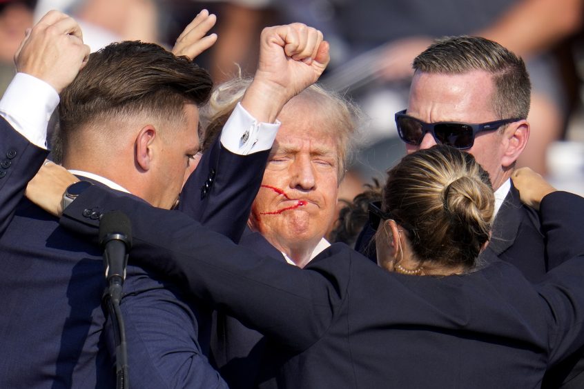 Former president Donald Trump pumps his fist as he is helped off the stage by US Secret Service agents after the assassination attempt (Gene J Puskar/AP)