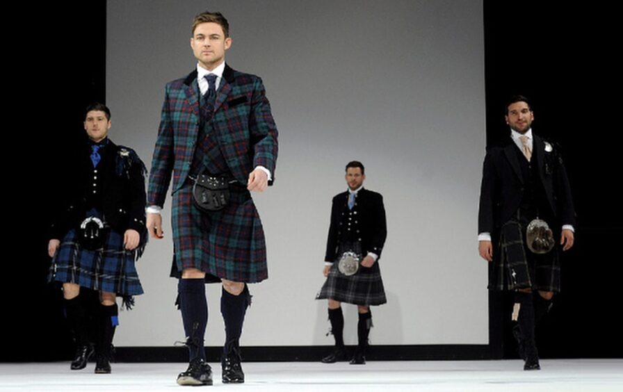 four men model kilts on a runway