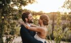 couple embraces in the countryside after planning a wedding in Scotland