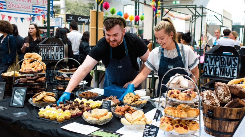 a man and woman prepare baked goods at a weekend market