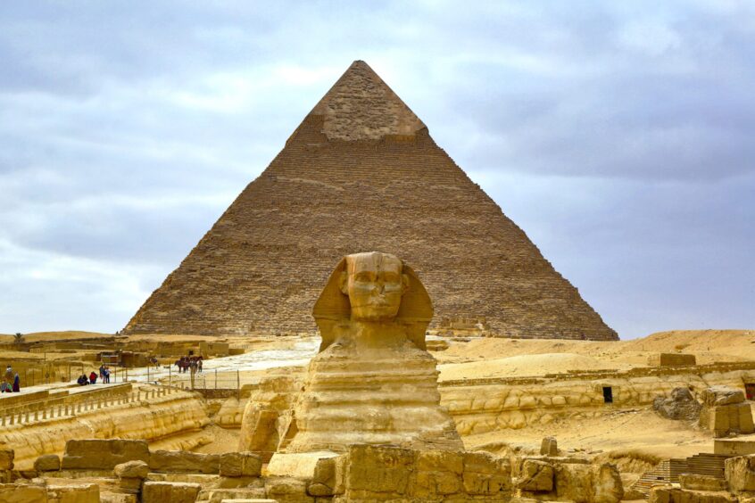 The Great Sphinx in front of a pyramid in Giza, Egypt.