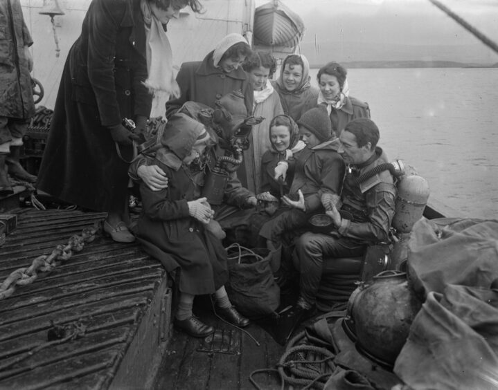 Children share in the spoils of their scallop diving in the sandy bay.