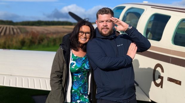 Grado and Judith Ralston in front of a small airplane in the grounds of the Newhall Mains in the Highlands.