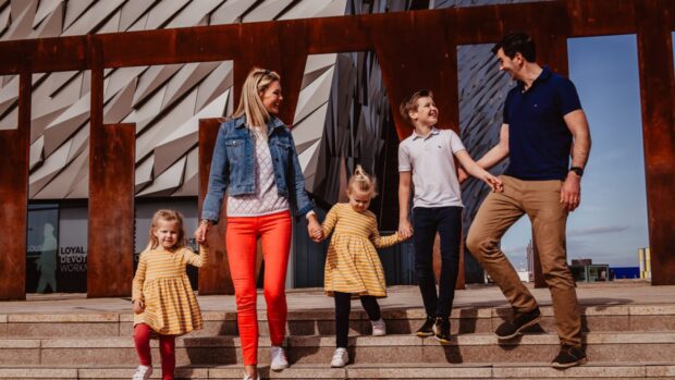 family smiling at one another while walking down steps after booking a coach from Glasgow to Belfast