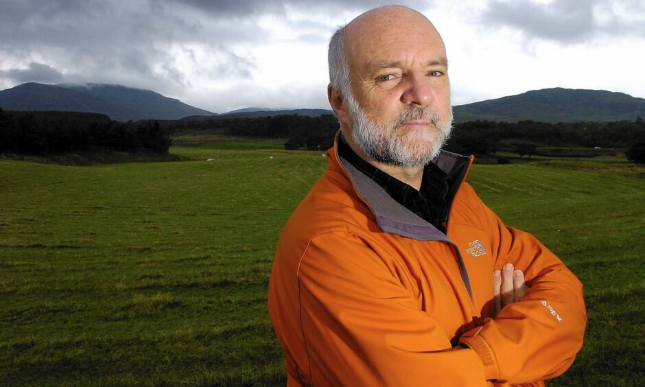 Broadcaster Cameron McNeish on a dark and foreboding landscape. McNeish is wearing an orange jacket.
