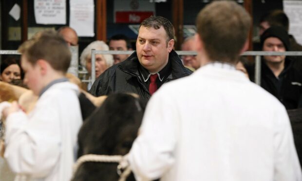 Blair Duffton, pictured centre judging a Young Farmers cattle contest, took the top honours on the hook in the carcase cattle contest.