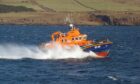 The orange and blue tobermory lifeboat heads out to sea.