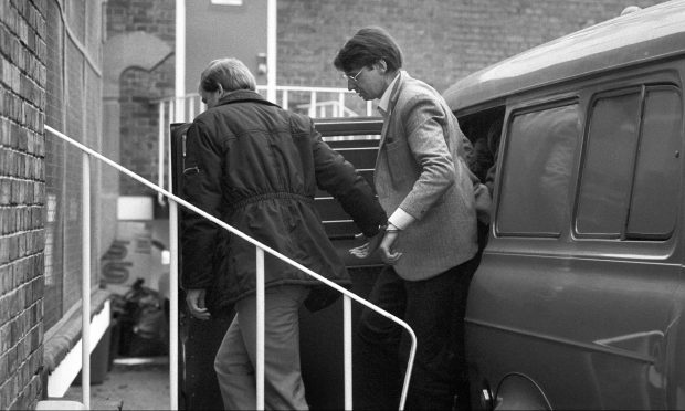 Dennis Nilsen being led out a car handcuffed to another man