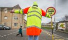 Lollipop person helping child across the road.