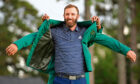Tiger Woods helps Masters champion Dustin Johnson with his green jacket after his victory at the Masters in 2020.