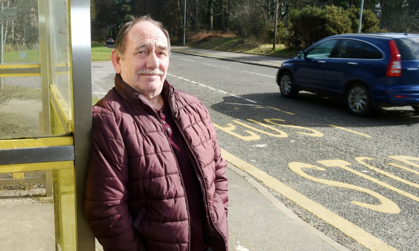 Alastair Kennedy leaning on the edge of a bus stop in Elgin. 