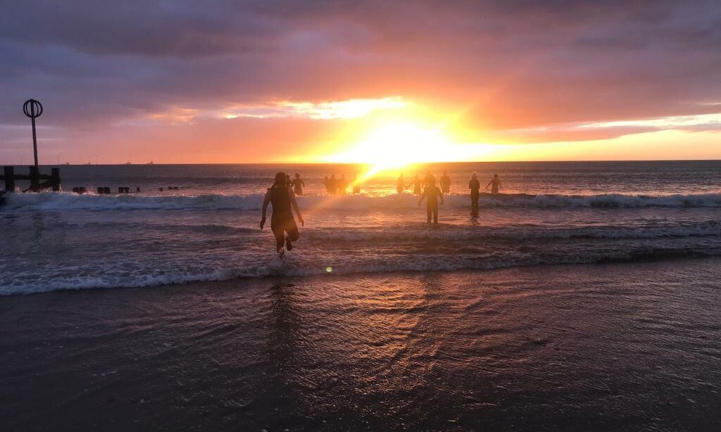 People running into the sea at sunrise