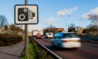Picture shows blurred traffic and a speed camera sign.
