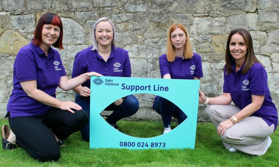 Members of Sight Scotland with a sign that shows their helpline number. Telephone number: 0800 024 8973
