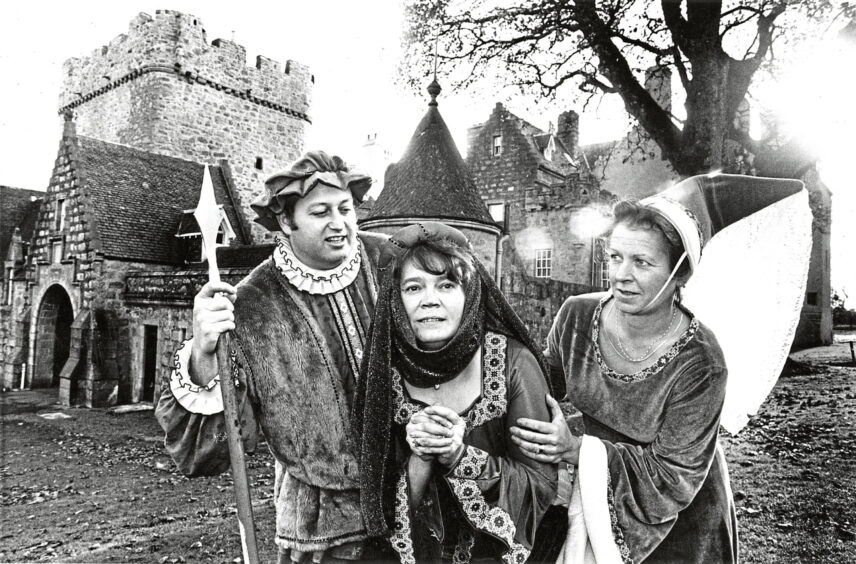 Three people in medieval costumes standing outside Drum Castle for Children In Need