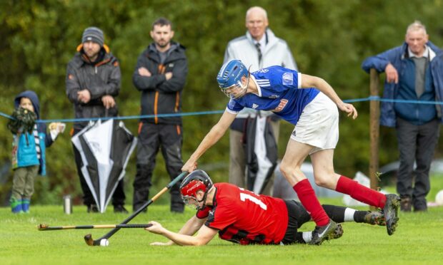 Oban's Daniel MacVicar (grounded) with Murdo Macrae (Kyles).  Celtic Society Cup Final, Oban Camanachd v Kyles Athletic, played at Taynuilt.; 6c89c4f0-8911-4d26-8e9a-47b0ba3c42d6