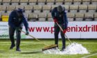 Groundstaff try to clear water off the pitch on Wednesday night.