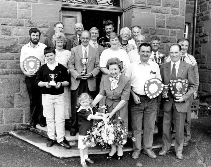 1990: Receiving a lovely floral arrangement from four-year-old Siobhan Aboyne - watched by winners from the Aberdeen Allotments and Gardens Society show - is Anne Cocker, who presented trophies at the event.