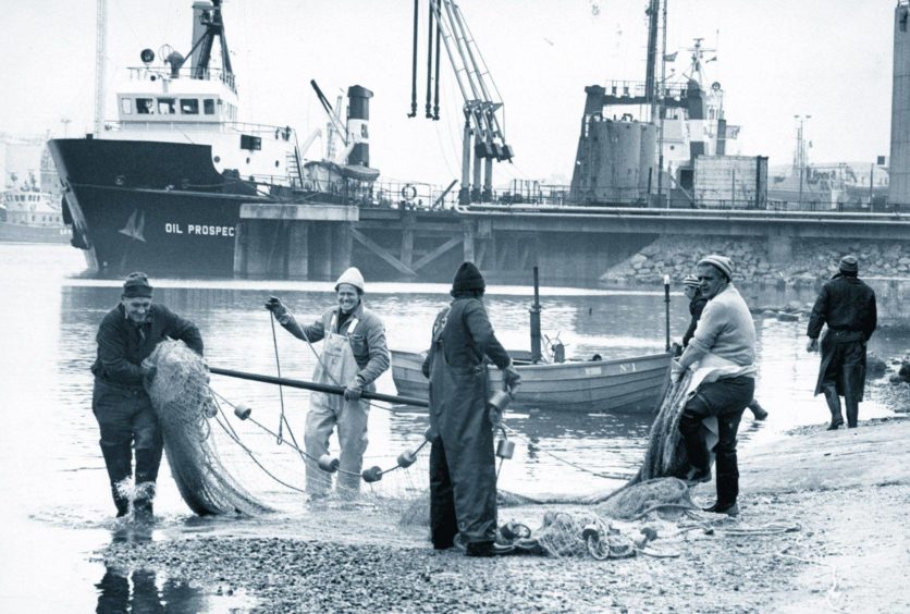 1978: The old and the new merge in this picture from April 1978 at the River Dee downstream of the Victoria Bridge, Torry, as salmon fishers haul in their nets against the background of oil industry supply vessel Oil Prospector.