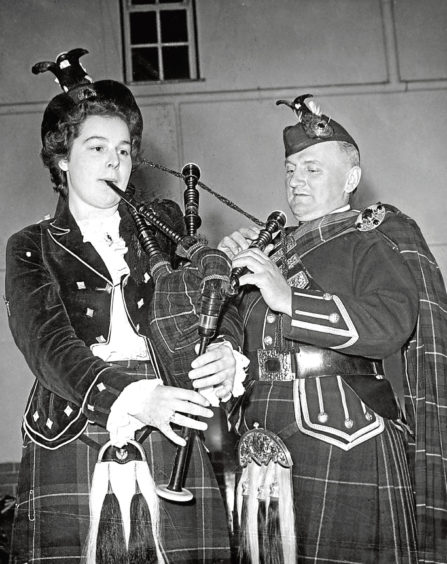 1955: Pipe Major G Hepburn, of Turriff Pipe Band, helps Miss Elma Reid with the tuning of the pipes.