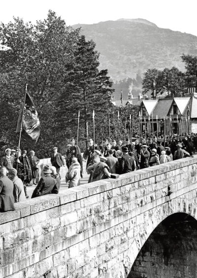 1928: Clan Duff cross the Bridge of Cluny during the march of the clans in this atmospheric photo.