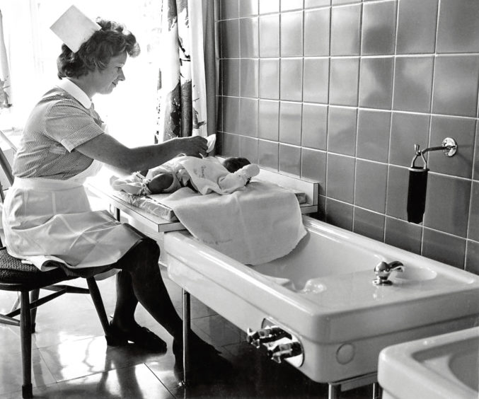 1972: A nurse bathes a baby at the spacious nursery located within Inverurie Hospital.