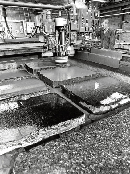 1975: Bob Taylor polishes seven granite slabs at once with an automatic polisher at Robertson Granite Yard.