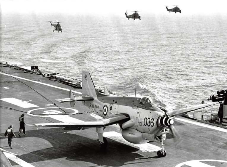 1964: A Fairey Gannet aircraft, part of Britain’s Early Warning System, lands on the aircraft carrier Ark Royal with three helicopters standing by.