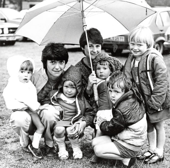 Julia Duguid, left, with her children Michelle, 2, and Louise, 3, share an umbrella with Anne Ogston and her youngsters Sarah, 2, Steven, 4, and Lynne, 5, at the show