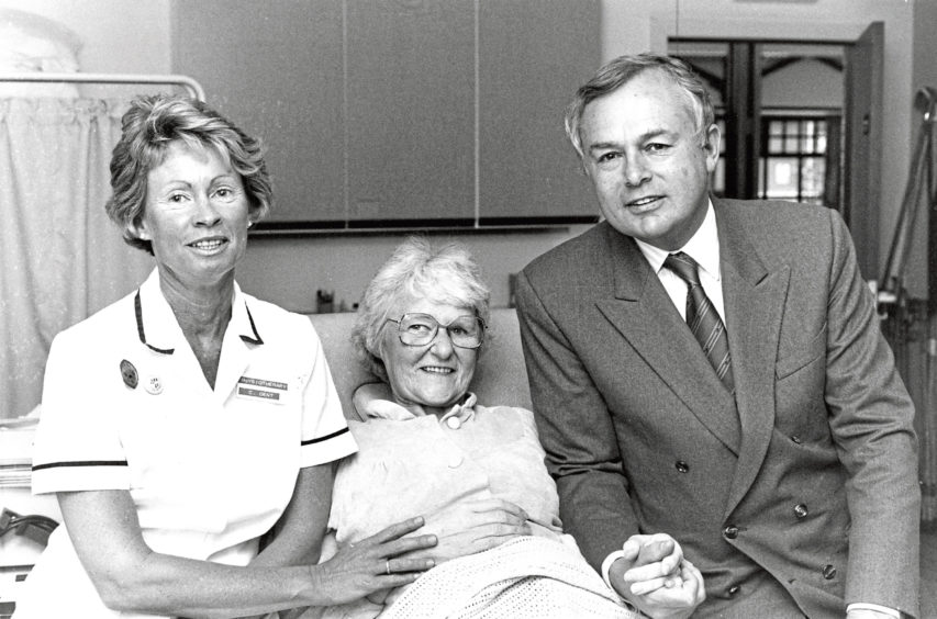 1992: BBC newscaster Martyn Lewis chats with patient  Anna Scott and physiotherapist Caroline Dent