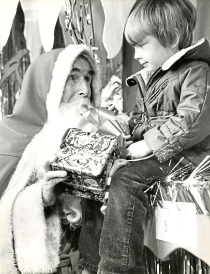 1983: Santa listens to some Christmas wishes from a young visitor to the Smurfs’ Cave grotto in Aberdeen’s Arnotts stor
