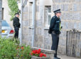 Police stand guard outside the couple's West End home