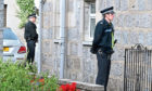 Police stand guard outside the couple's West End home