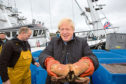 Prime Minister Boris Johnson holds crabs caught on the Carvela with Karl Adamson at Stromness Harbour