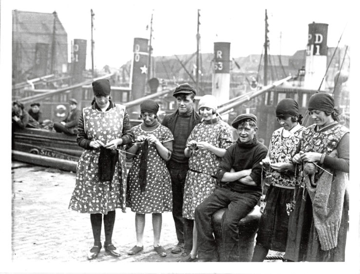 1930s: Taking a break at Peterhead harbour, the fisher lasses get on with the knitting for their menfolk.