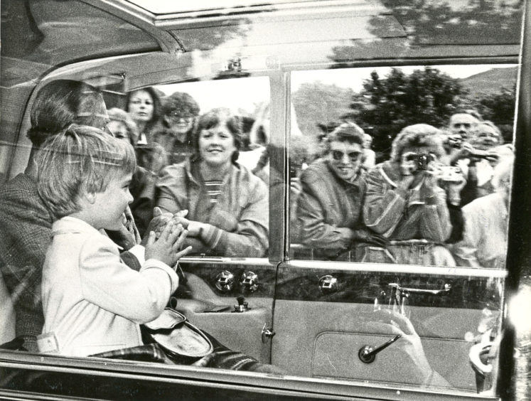 1987: Prince William waving at the crowds from the car, where he was sitting in between The Queen and the Duke of Edinburgh. The Royal family were going to Crathie Church.