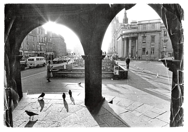 1978: Light and shade has been very much in evidence with the lovely autumn weather we have been having. The picture was taken looking through the Mercat Cross in the Castlegate as the sun sparkles. Even the pigeons are basking in the sun while waiting for a passer-by to throw them some tit bit.