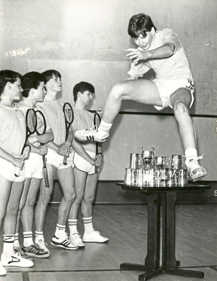 1986: All conquering Aberdeen Squash Racquets Club juniors captain Richard Irvine leaps over some of the trophies the side have won this season watched by (from left) Scott Wilson, Matthew Smith, David Irvine and Fraser Gordon. The team are looking for a sponsor to help with travelling costs.