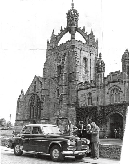 1956 - A group of men gather beside a stylish vehicle parked in front of King’s College